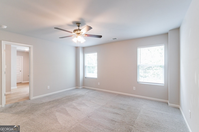 unfurnished room featuring plenty of natural light, ceiling fan, and light carpet