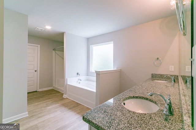 bathroom featuring hardwood / wood-style floors, a washtub, and vanity