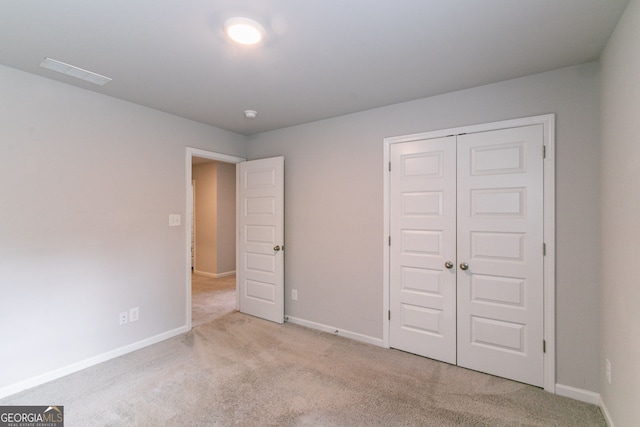 unfurnished bedroom with light colored carpet and a closet