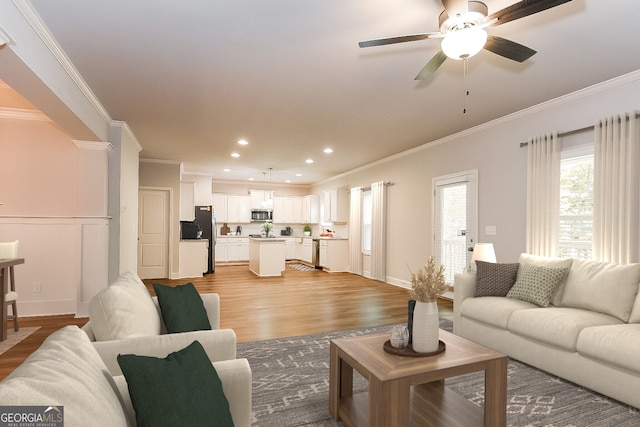 living room with ceiling fan, ornamental molding, and light hardwood / wood-style floors