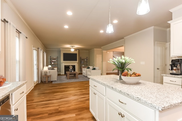 kitchen featuring white cabinets, a kitchen island, light wood-type flooring, decorative light fixtures, and ornamental molding