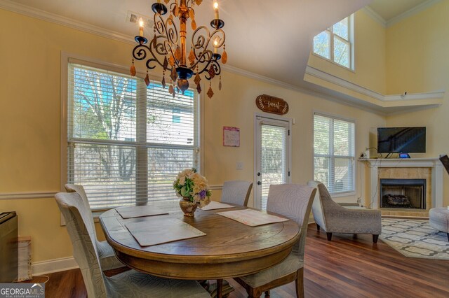 dining room with a notable chandelier, dark hardwood / wood-style floors, ornamental molding, and a healthy amount of sunlight