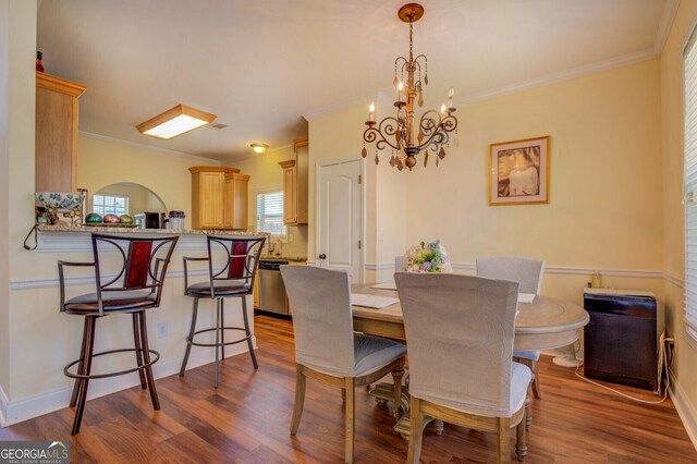 dining space featuring crown molding, an inviting chandelier, and hardwood / wood-style flooring