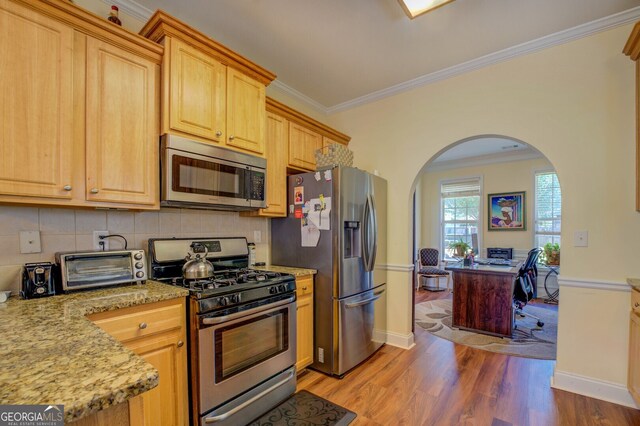 kitchen featuring light stone countertops, stainless steel appliances, hardwood / wood-style floors, and crown molding