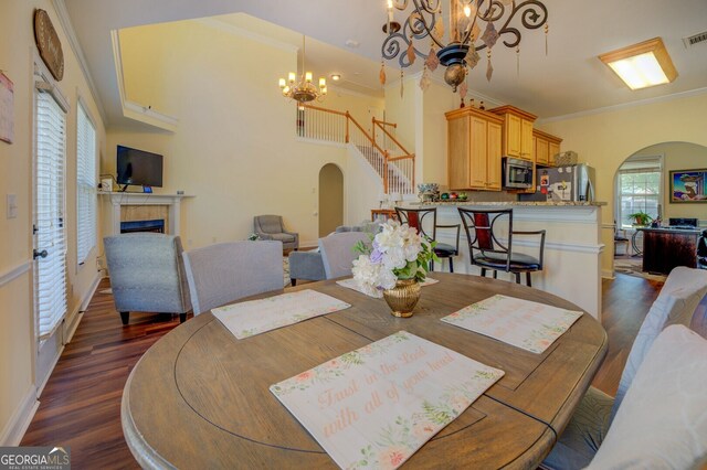 dining area featuring a fireplace, dark hardwood / wood-style floors, ornamental molding, and a chandelier