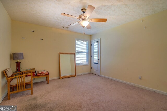 spare room featuring ceiling fan, light colored carpet, and a textured ceiling