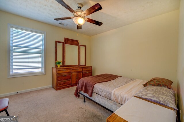 carpeted bedroom featuring ceiling fan and a textured ceiling