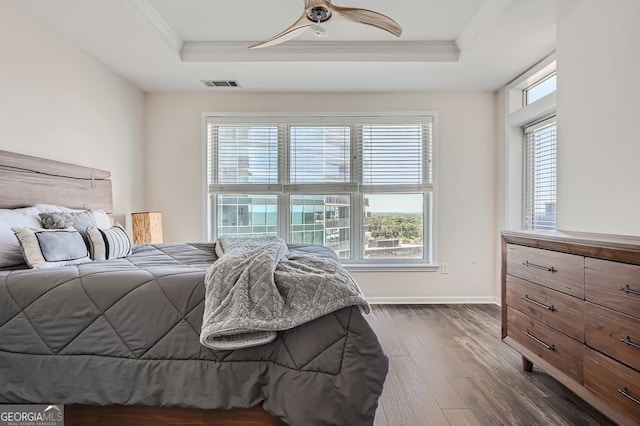 bedroom featuring ceiling fan, ornamental molding, a raised ceiling, and dark wood-type flooring