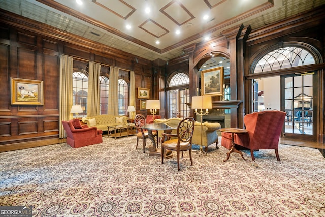 sitting room featuring ornamental molding, wood walls, a high ceiling, and light colored carpet