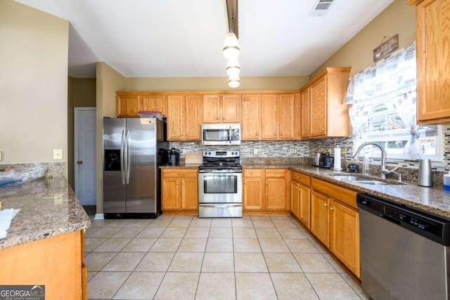 kitchen featuring pendant lighting, light tile patterned flooring, sink, stainless steel appliances, and stone countertops