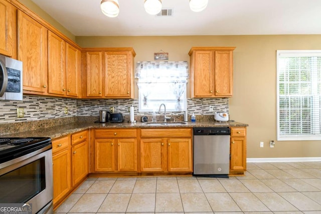 kitchen with light tile patterned floors, appliances with stainless steel finishes, sink, and tasteful backsplash