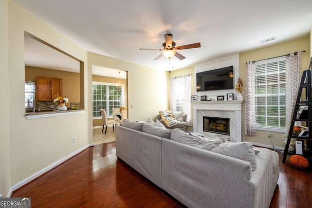 living room with ceiling fan, a fireplace, and dark wood-type flooring