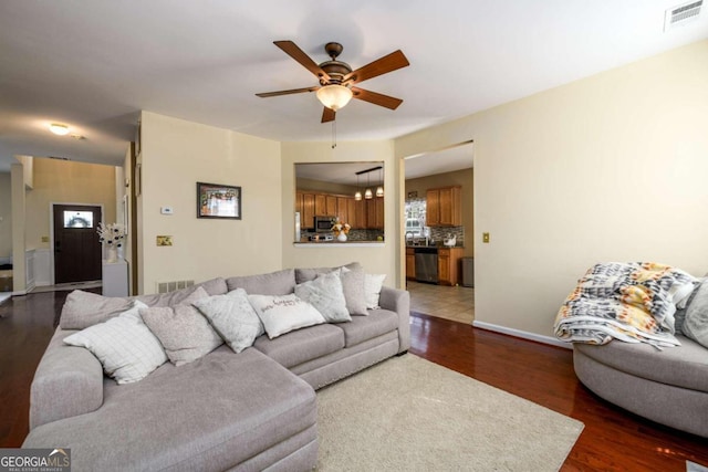 living room featuring ceiling fan and dark hardwood / wood-style floors