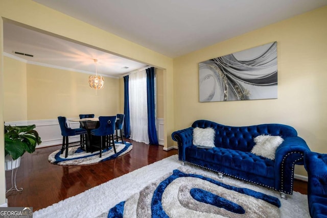 living room with wood-type flooring, a notable chandelier, and ornamental molding