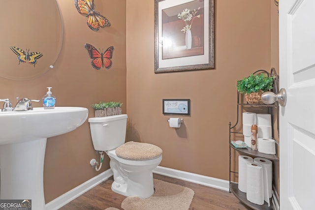 bathroom with wood-type flooring, toilet, and sink