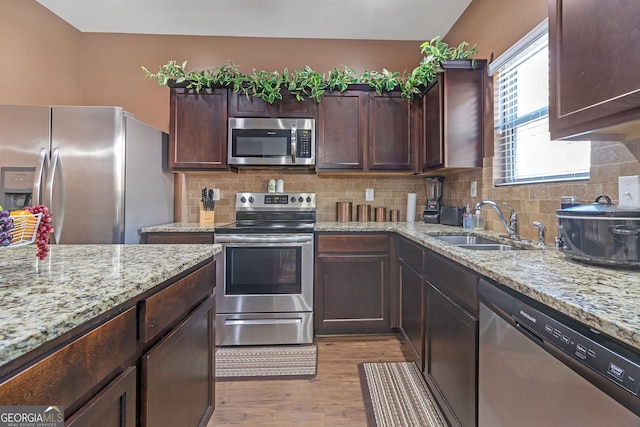 kitchen with light stone countertops, light hardwood / wood-style floors, sink, and stainless steel appliances