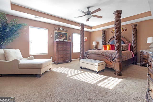 bedroom featuring carpet flooring, multiple windows, a raised ceiling, and ceiling fan