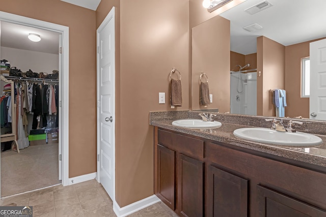 bathroom with tile patterned flooring, a shower, and vanity