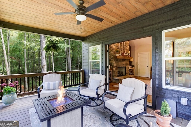 sunroom with ceiling fan, a fireplace, and wooden ceiling