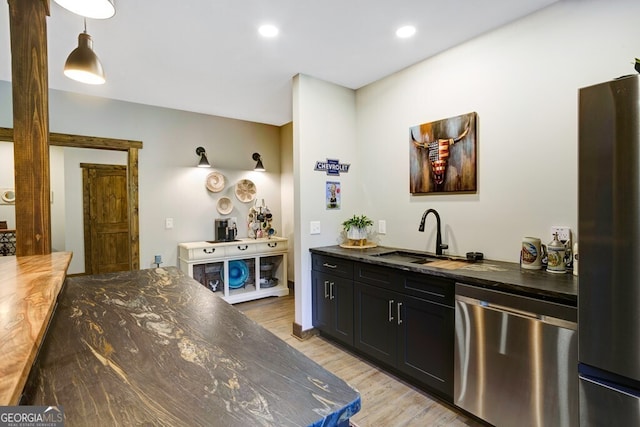 bar with light hardwood / wood-style flooring, appliances with stainless steel finishes, pendant lighting, and sink