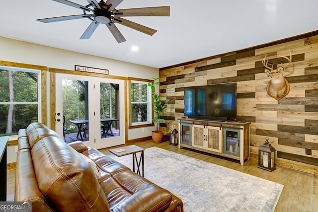 living room featuring ceiling fan, wooden walls, and light wood-type flooring