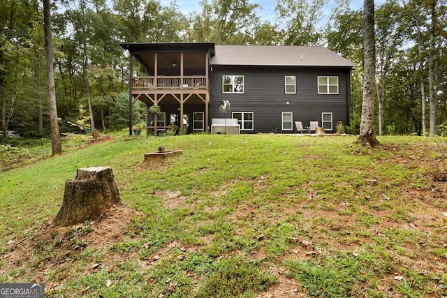 rear view of house featuring a lawn and a sunroom