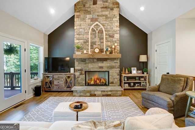 living room featuring wood-type flooring, a fireplace, and high vaulted ceiling