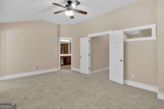 unfurnished bedroom featuring ceiling fan, lofted ceiling, light carpet, and ensuite bathroom