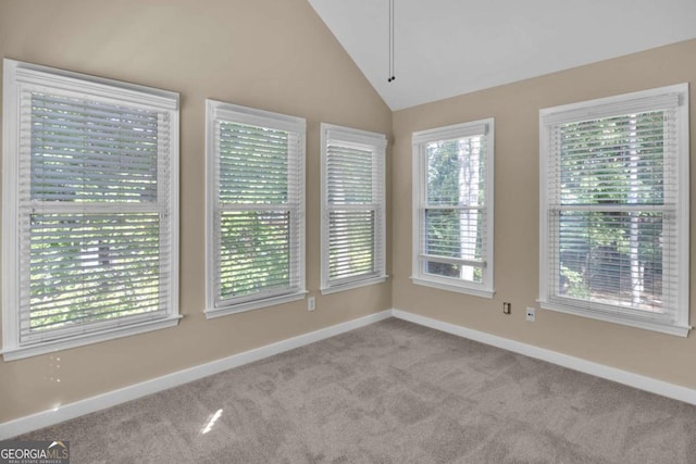 unfurnished room with light colored carpet, plenty of natural light, and high vaulted ceiling