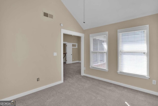 carpeted spare room featuring high vaulted ceiling