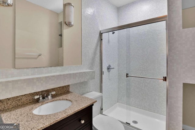 bathroom with walk in shower, vanity, backsplash, and toilet