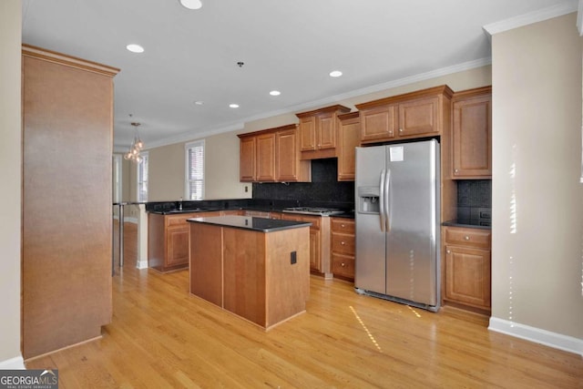 kitchen featuring appliances with stainless steel finishes, light hardwood / wood-style floors, kitchen peninsula, a kitchen island, and crown molding