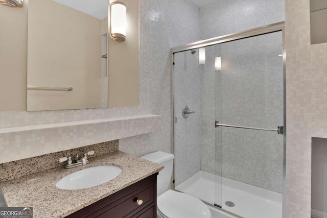 bathroom with vanity, tasteful backsplash, tile walls, toilet, and a shower with door