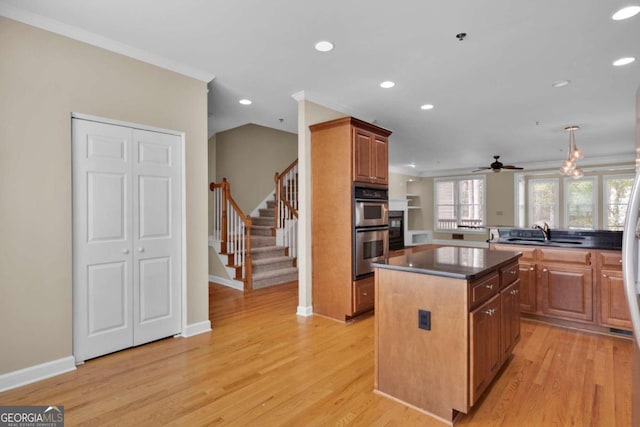 kitchen featuring stainless steel double oven, light hardwood / wood-style flooring, sink, and a center island