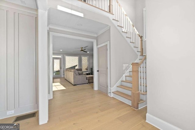 foyer featuring light hardwood / wood-style floors, ornamental molding, and ceiling fan