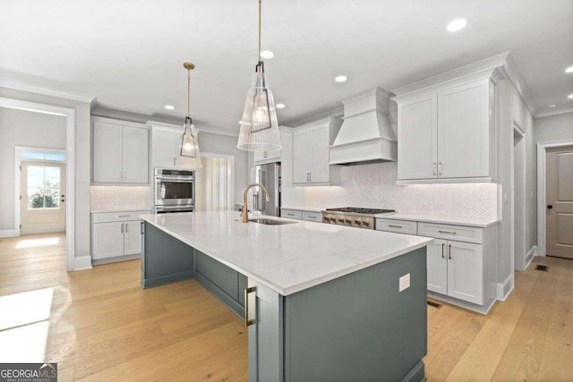 kitchen featuring light hardwood / wood-style floors, premium range hood, a kitchen island with sink, and sink