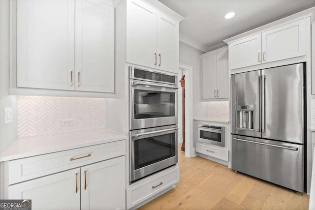 kitchen featuring decorative backsplash, stainless steel appliances, white cabinets, and light wood-type flooring