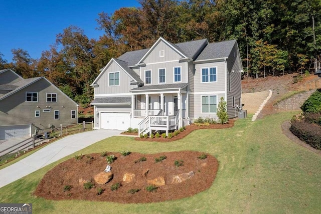 view of front of property featuring a front yard, cooling unit, a garage, and covered porch