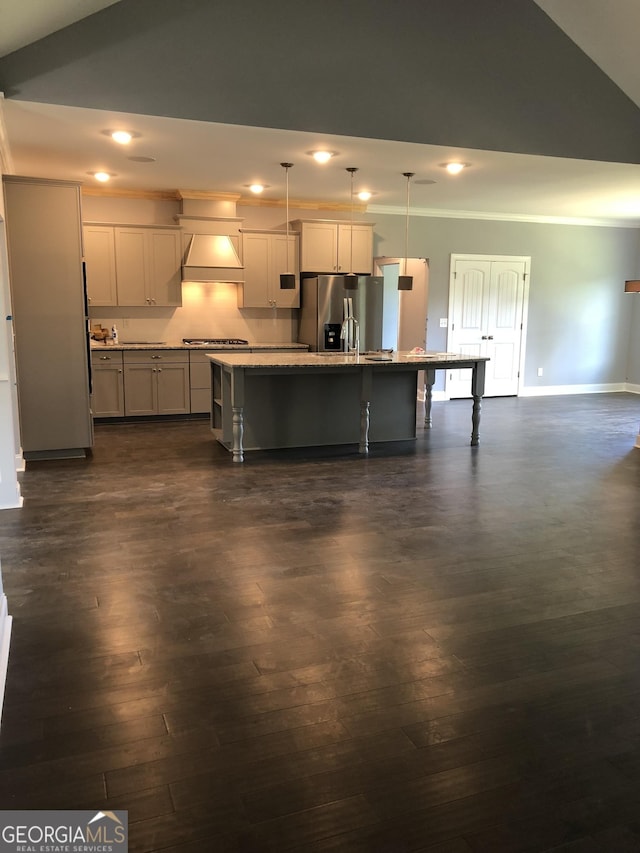 kitchen featuring stainless steel appliances, a kitchen island with sink, a breakfast bar area, and decorative light fixtures