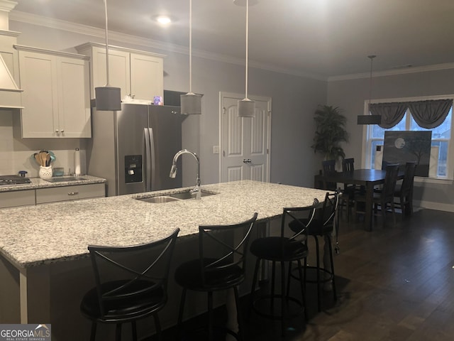 kitchen featuring decorative light fixtures, sink, a kitchen island with sink, light stone counters, and stainless steel appliances