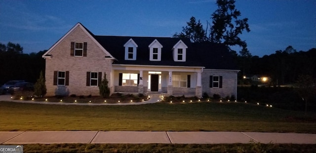 cape cod home featuring a front yard and covered porch