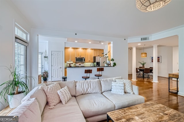 living room featuring light hardwood / wood-style flooring, crown molding, and ornate columns