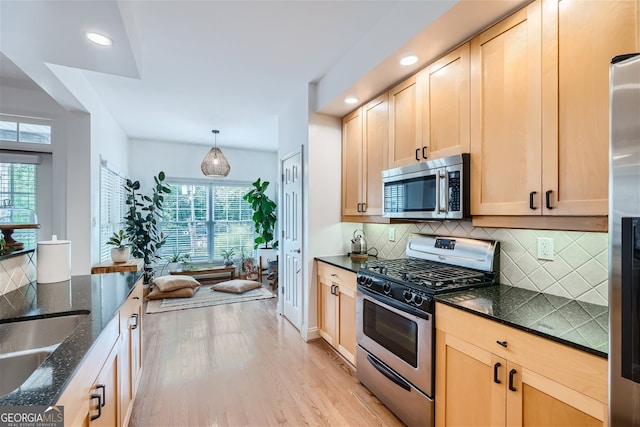 kitchen with light brown cabinetry, light hardwood / wood-style flooring, stainless steel appliances, and a wealth of natural light