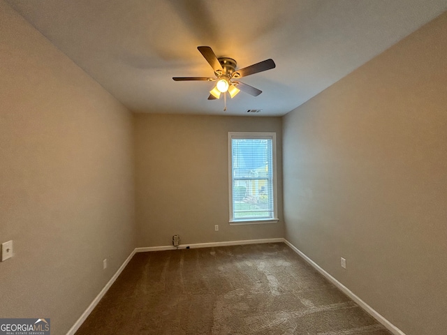 empty room with ceiling fan and dark carpet