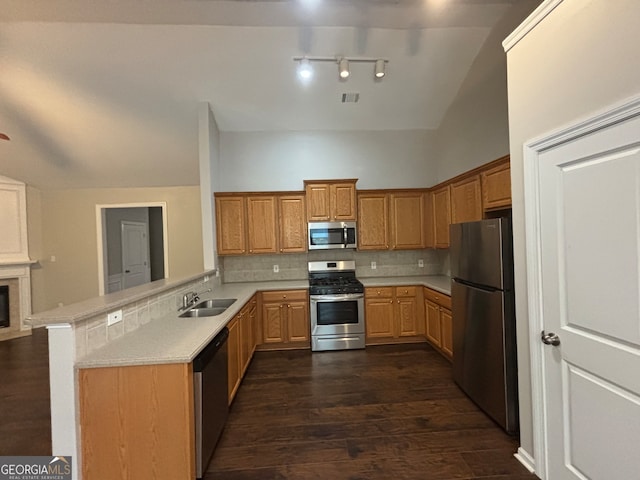 kitchen with appliances with stainless steel finishes, backsplash, kitchen peninsula, dark hardwood / wood-style floors, and sink