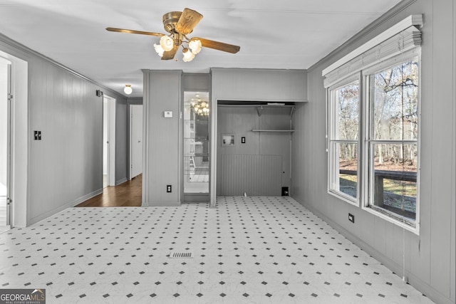 interior space featuring wooden walls, ceiling fan, and crown molding