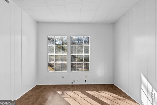 empty room with dark hardwood / wood-style floors and wooden walls