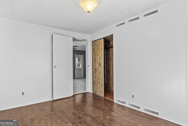 unfurnished room featuring dark hardwood / wood-style floors, ceiling fan, and wood walls