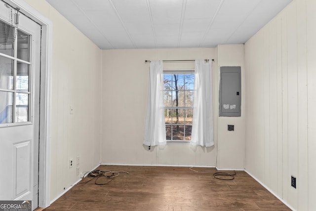 spare room featuring electric panel, wooden walls, and hardwood / wood-style flooring