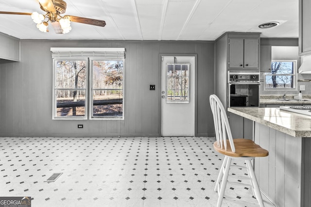 kitchen with a kitchen bar, gray cabinets, plenty of natural light, and oven